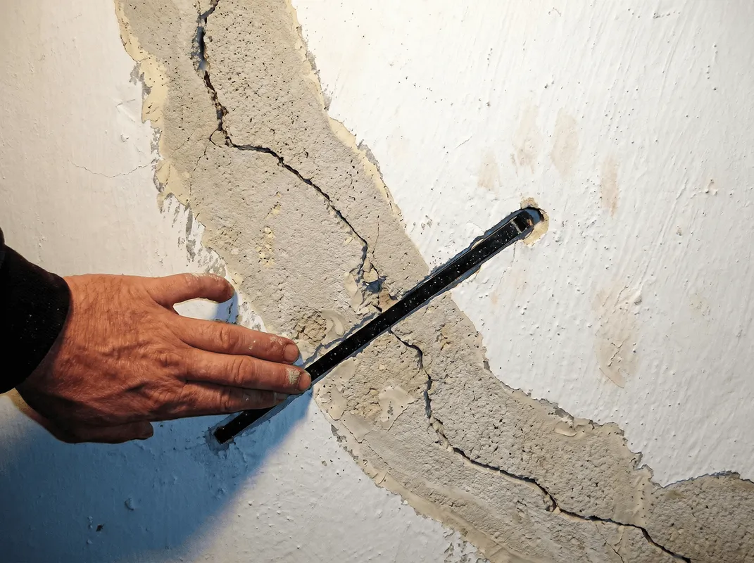 A wall with a large crack is being inspected by a professional in Miami, FL